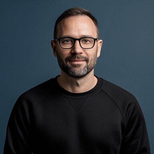 Ein Mann mit Brille und Bart und einem dunklen Sweatshirt